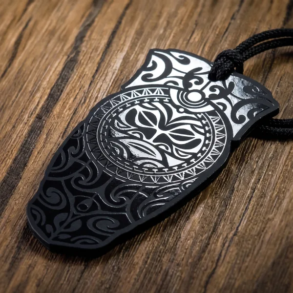 A black hang tag laser-engraved with a silver tribal pattern, strung with black cord.