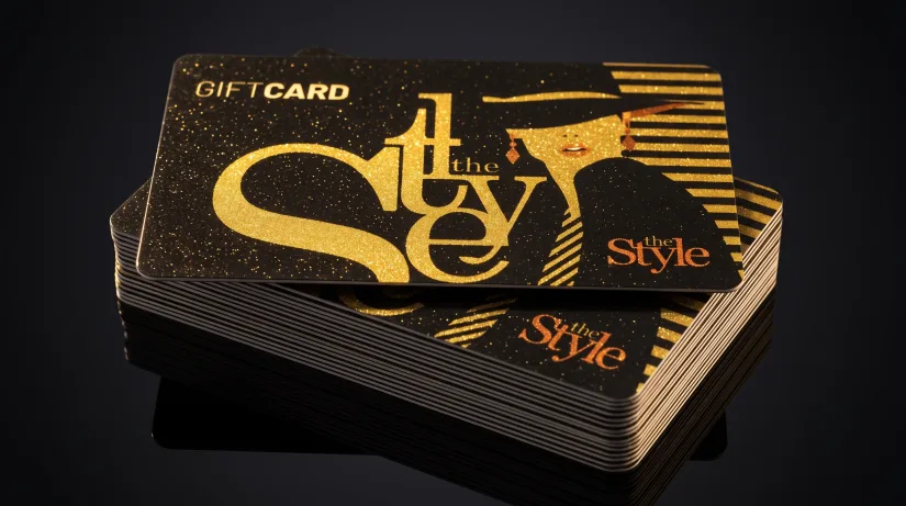 A glossy black and gold glitter plastic gift card stack reading "the Style."
