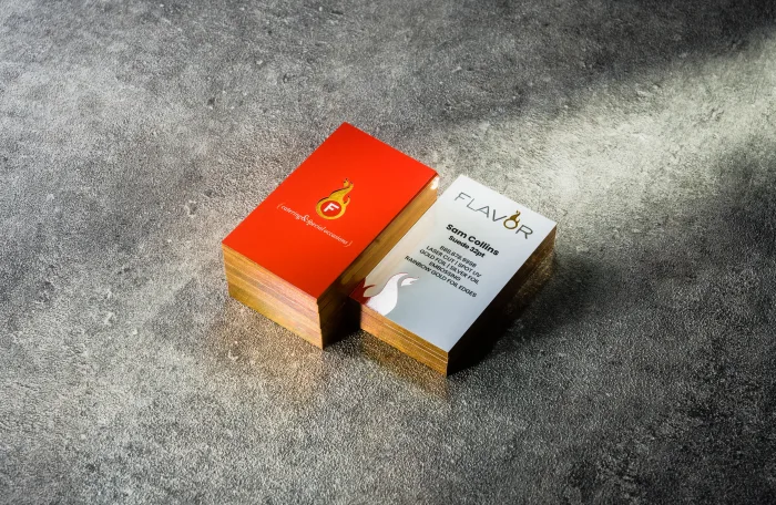 A red "Flavor" Spot UV card standing beside its cream Suede sibling card with a gold foiled edge.